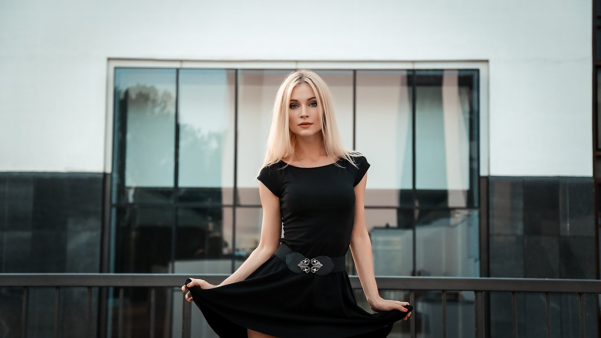 Блондинка в коротком черном платье стоит спиной