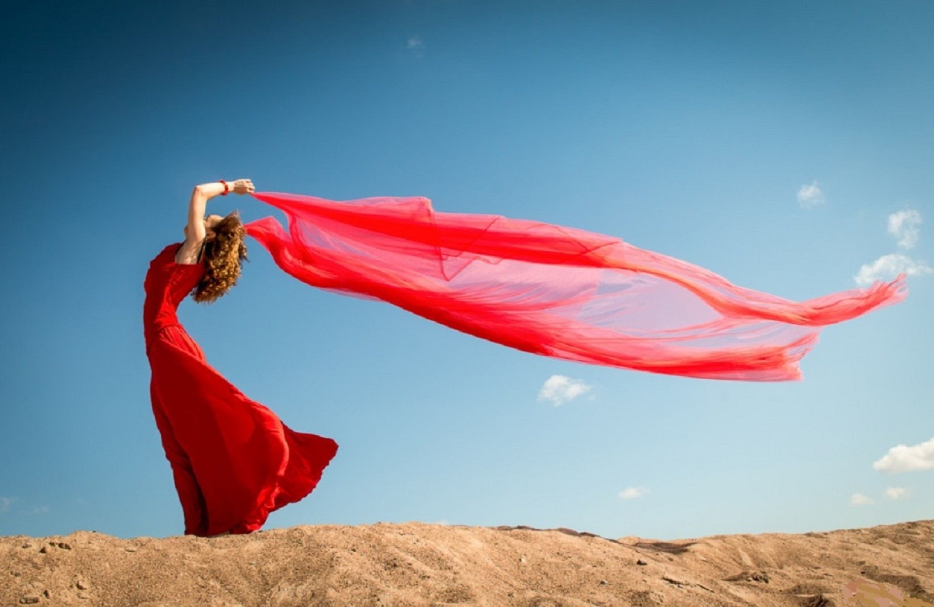 Красная бай. Развивающееся платье. Девушка в длинном платье. Ткань развивается на ветру. Платье развивается на ветру.