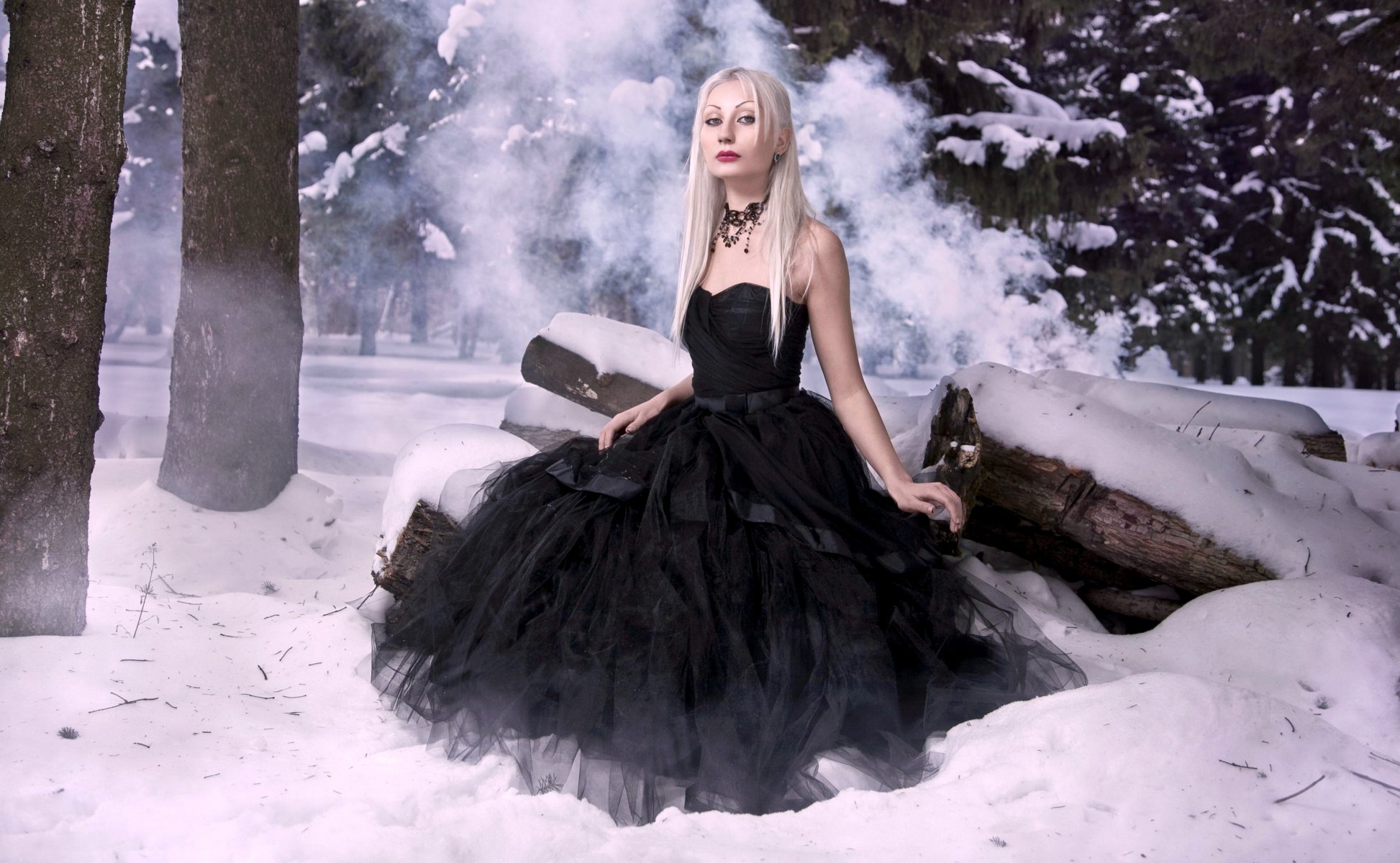 Молодая девушка в старинном платье сидит на снегу